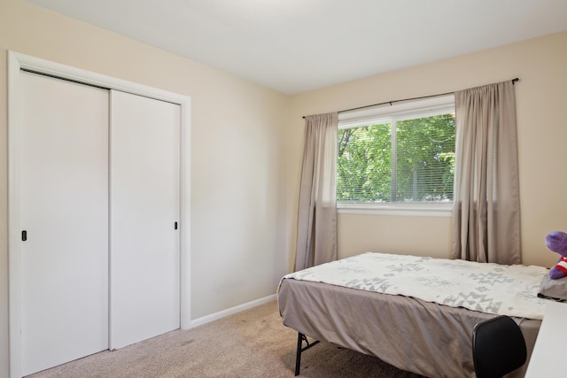 bedroom with light carpet, a closet, and baseboards