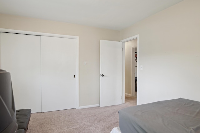 carpeted bedroom featuring a closet and baseboards