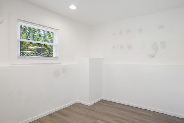 empty room featuring wood finished floors, baseboards, and recessed lighting