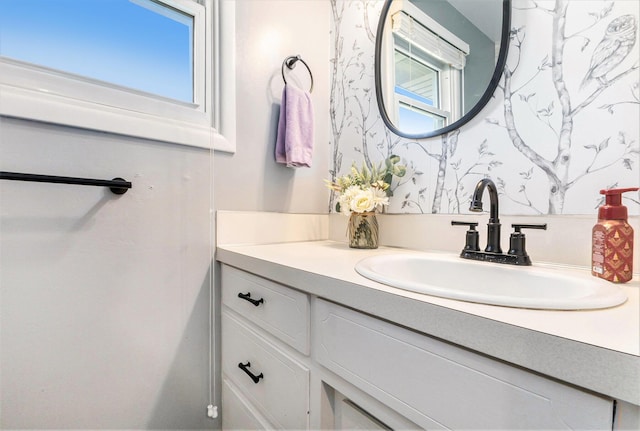 bathroom featuring vanity, wallpapered walls, and plenty of natural light