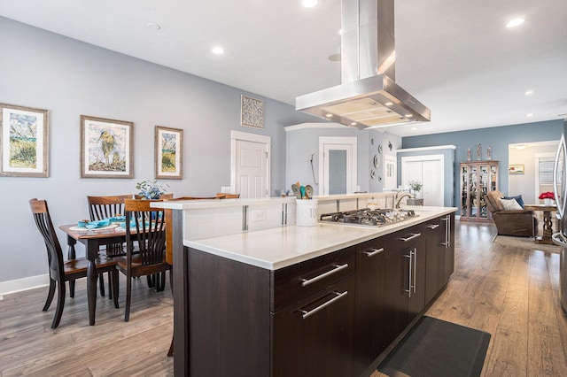 3080 Silver Fir Ct, Holland, MI 49424 - kitchen featuring island exhaust hood, stainless steel gas stovetop, light wood-type flooring, light countertops, and dark brown cabinetry