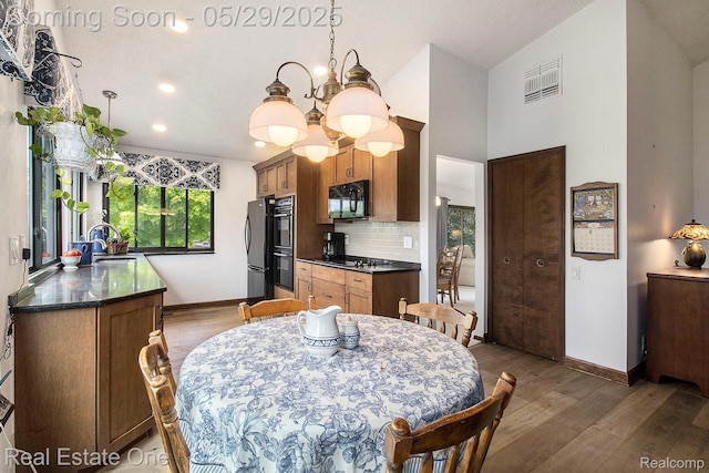 4976 Ledgewood Dr, Commerce Twp, MI 48382 - dining space featuring a chandelier, wood finished floors, vaulted ceiling, and recessed lighting