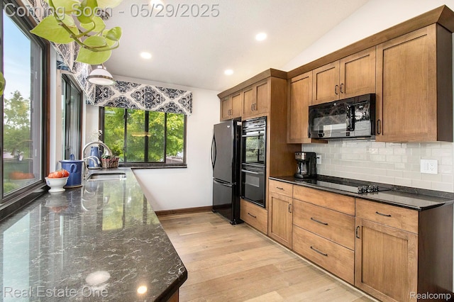 4976 Ledgewood Dr, Commerce Twp, MI 48382 - kitchen featuring black appliances, decorative backsplash, brown cabinets, dark stone countertops, and light wood-style flooring