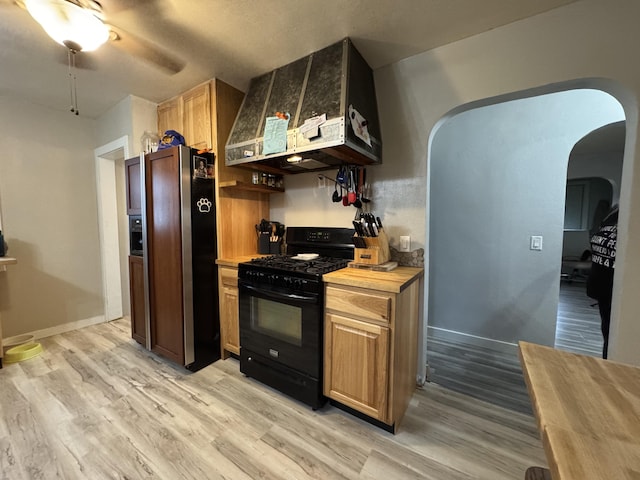 14700 9 Mile Rd, Kaleva, MI 49645 - kitchen featuring black appliances, arched walkways, light wood-style floors, ceiling fan, and butcher block counters