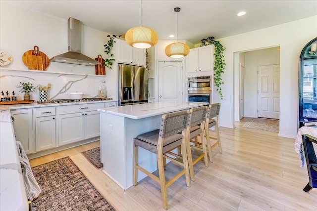 5134 Muirfield Ln, Clarkston, MI 48348 - kitchen featuring wall chimney exhaust hood, stainless steel appliances, a kitchen breakfast bar, decorative backsplash, and light wood finished floors