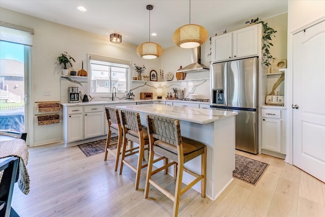 5134 Muirfield Ln, Clarkston, MI 48348 - kitchen with appliances with stainless steel finishes, wall chimney range hood, open shelves, a breakfast bar, and light wood-style floors