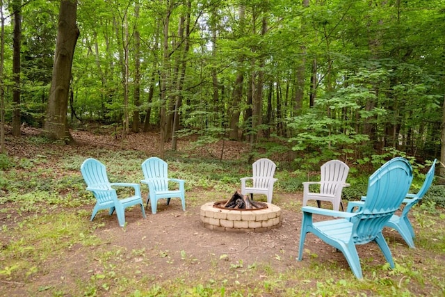 view of yard with an outdoor fire pit and a view of trees
