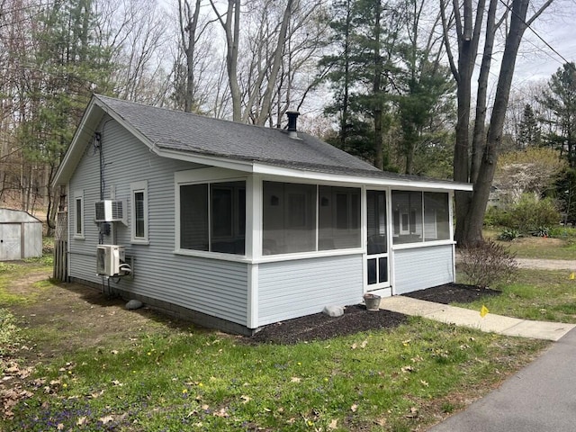 view of side of property with a sunroom, roof with shingles, an outdoor structure, a storage unit, and a cooling unit