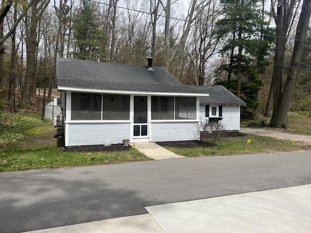view of front facade with a sunroom and a shingled roof
