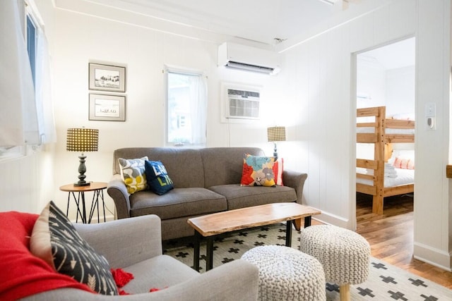 living area featuring a wall mounted AC, wood finished floors, an AC wall unit, and baseboards
