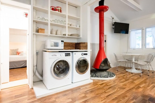 laundry area with wood finished floors, independent washer and dryer, and a wood stove