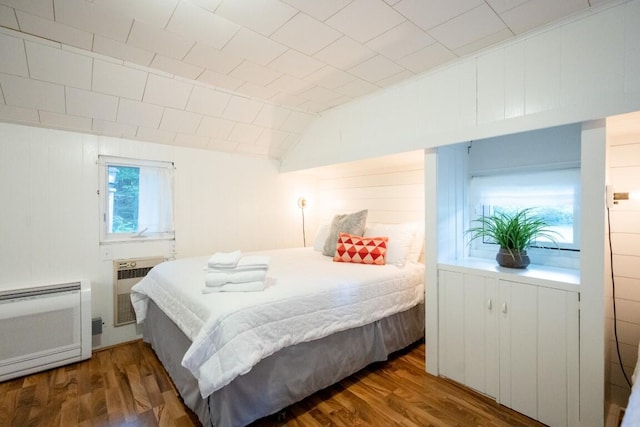 bedroom with wood finished floors, heating unit, and lofted ceiling