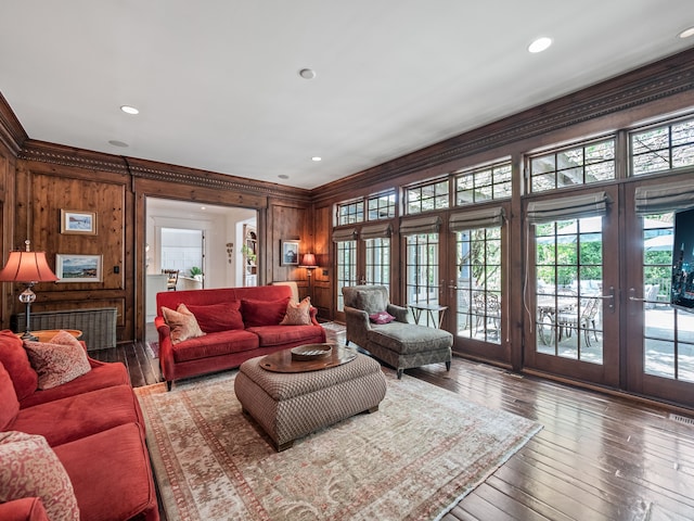 living room featuring french doors, wood walls, ornamental molding, hardwood / wood-style floors, and recessed lighting