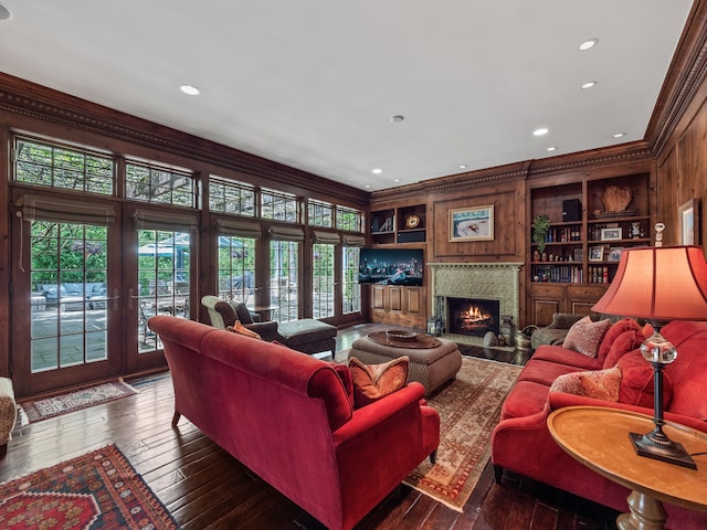living area with crown molding, wood-type flooring, a fireplace, french doors, and built in features