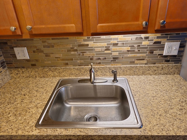 kitchen view of a sink, backsplash, and brown cabinets