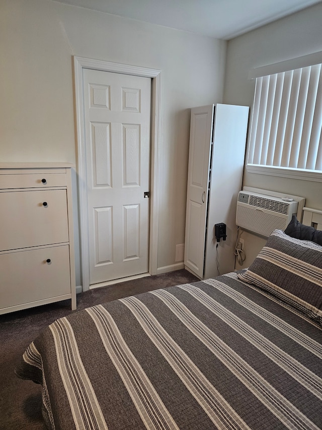bedroom with dark carpet, a wall mounted AC, and baseboards