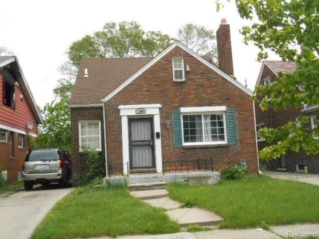 view of front of home featuring brick siding, a chimney, and a front yard
