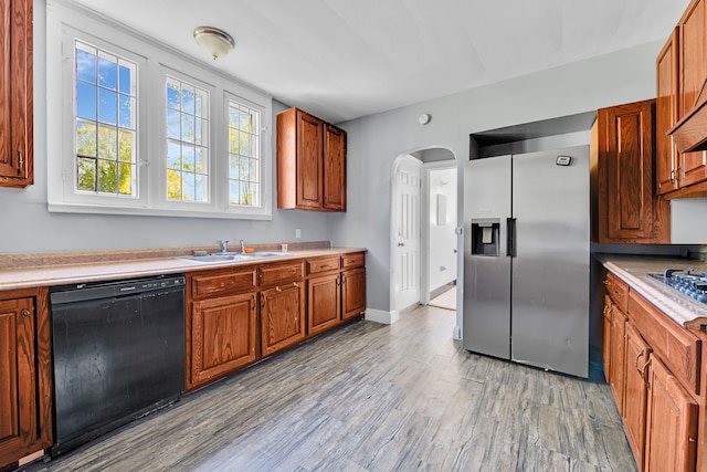 3835 Courville St, Detroit, MI 48224 - kitchen with stainless steel refrigerator with ice dispenser, black dishwasher, a sink, arched walkways, and light wood finished floors