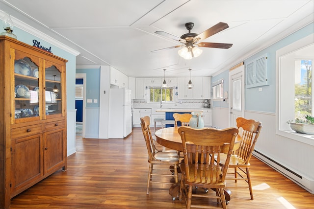 5303 Lake Rd, Reading, MI 49274 - dining room with a baseboard heating unit, ceiling fan, crown molding, wainscoting, and wood finished floors