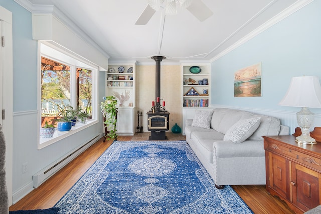 5303 Lake Rd, Reading, MI 49274 - living room with a wood stove, a baseboard heating unit, wood finished floors, a ceiling fan, and ornamental molding