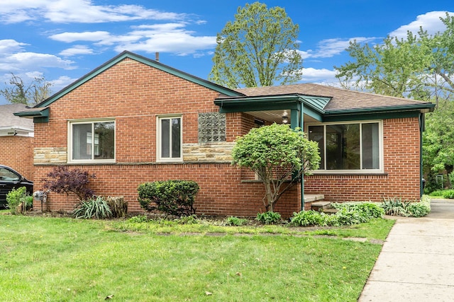 view of side of property with brick siding, a lawn, and a shingled roof