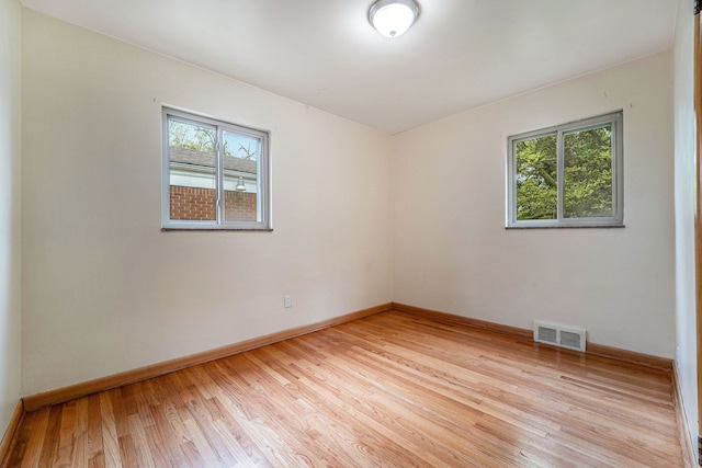 spare room featuring healthy amount of natural light, light wood-style flooring, and baseboards