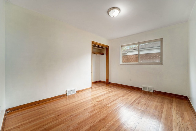 unfurnished bedroom featuring wood finished floors, baseboards, and a closet