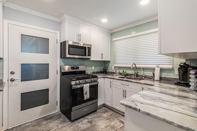 7262 Hatchery Rd, Waterford, MI 48327 - kitchen featuring appliances with stainless steel finishes, a sink, crown molding, white cabinetry, and tasteful backsplash