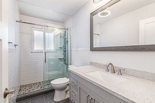 7262 Hatchery Rd, Waterford, MI 48327 - bathroom featuring tile walls, a shower stall, toilet, vanity, and wainscoting