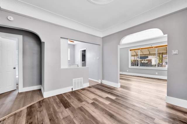 15430 Mendota St, Detroit, MI 48238 - unfurnished living room featuring arched walkways, baseboards, and wood finished floors