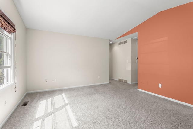 carpeted empty room with vaulted ceiling and baseboards