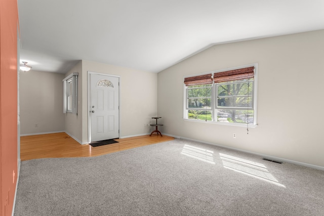 carpeted empty room featuring lofted ceiling and baseboards