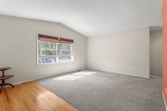 empty room with vaulted ceiling, baseboards, and carpet flooring