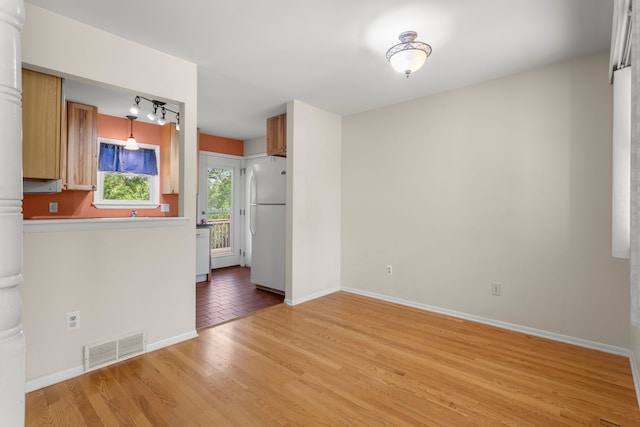 spare room with light wood finished floors, baseboards, and ornate columns