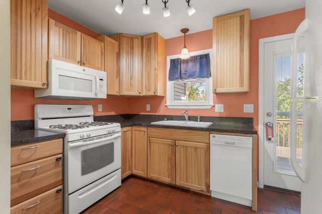 kitchen with white appliances, a sink, dark countertops, and hanging light fixtures