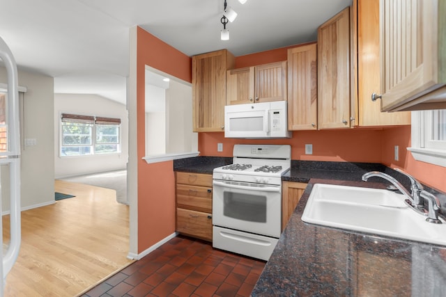 kitchen featuring white appliances, a sink, dark countertops, baseboards, and lofted ceiling