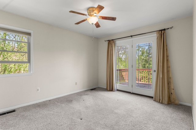 carpeted spare room featuring healthy amount of natural light, a ceiling fan, and baseboards