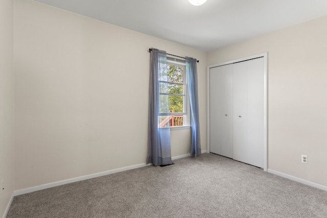 unfurnished bedroom with light carpet, baseboards, and a closet