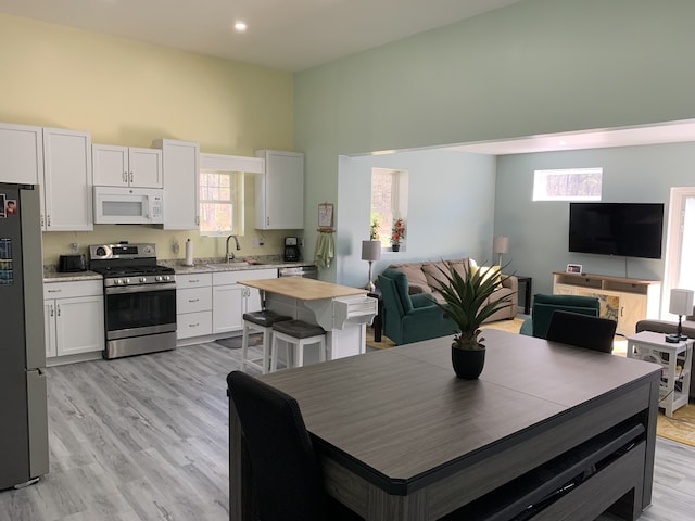 dining room with a high ceiling, light wood finished floors, and recessed lighting