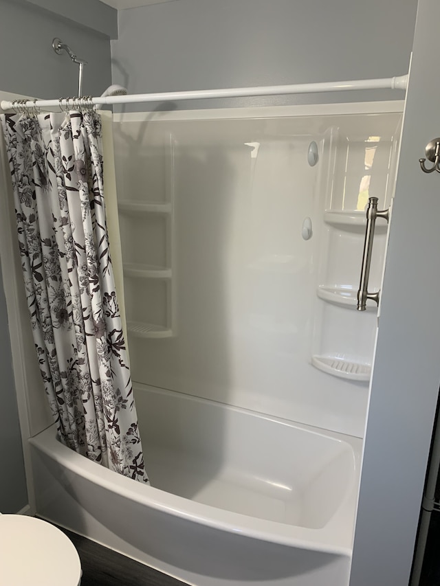bathroom featuring shower / tub combo and toilet
