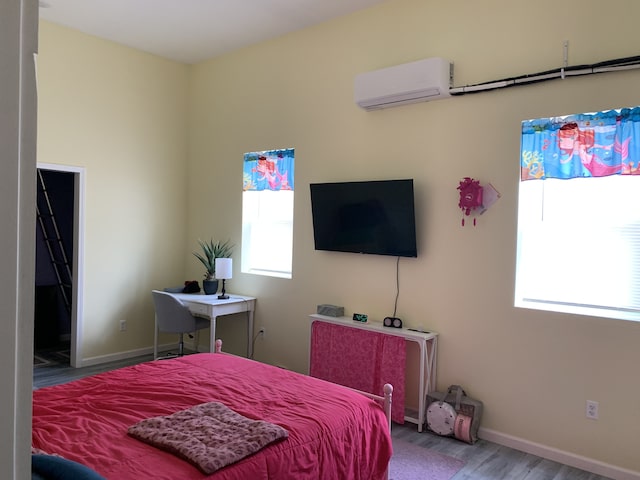 bedroom featuring a wall mounted air conditioner, wood finished floors, multiple windows, and baseboards