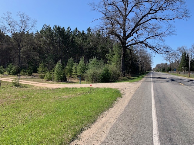 view of asphalt street with a view of trees