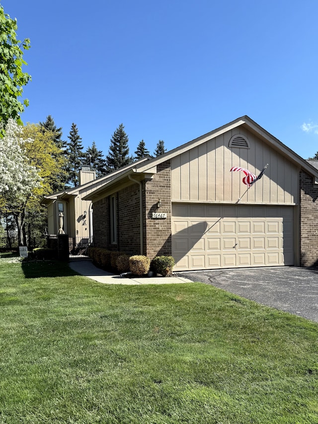 view of front of house featuring brick siding, a garage, driveway, and a front yard