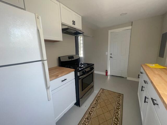 519 Whaley St, Cadillac, MI 49601 - kitchen featuring gas stove, freestanding refrigerator, butcher block countertops, and under cabinet range hood