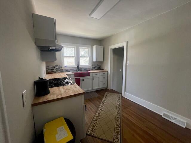 519 Whaley St, Cadillac, MI 49601 - kitchen featuring dark wood-style flooring, white cabinetry, baseboards, gas stovetop, and ventilation hood