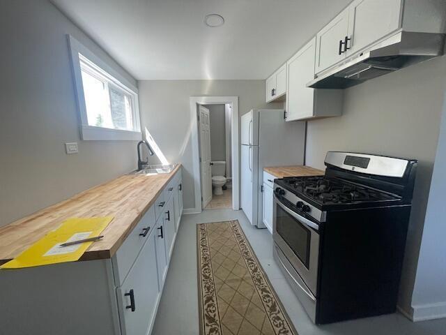 519 Whaley St, Cadillac, MI 49601 - kitchen featuring stainless steel range with gas cooktop, under cabinet range hood, a sink, butcher block countertops, and white cabinetry