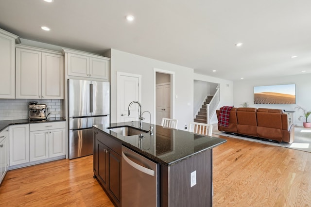 5534 Helmsdale Blvd, West Bloomfield, MI 48322 - kitchen featuring stainless steel appliances, a sink, light wood-style flooring, dark stone counters, and open floor plan