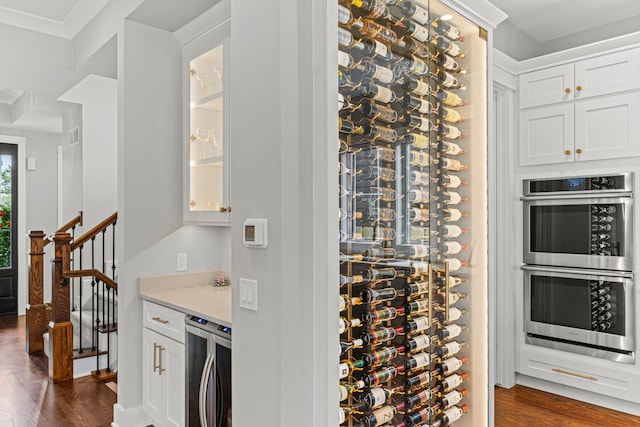 wine area featuring dark wood-type flooring, beverage cooler, and ornamental molding