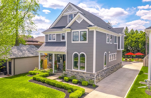 craftsman house featuring stone siding, a front yard, concrete driveway, a shingled roof, and covered porch