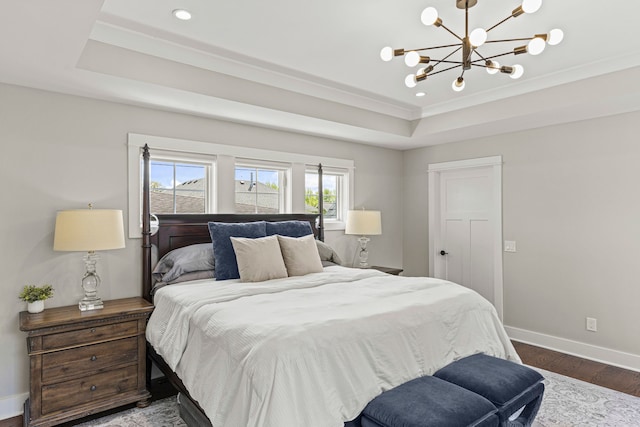 bedroom featuring baseboards, wood finished floors, a chandelier, ornamental molding, and a raised ceiling